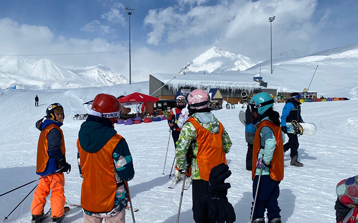 Students on the mountain in ski school being spoken to by their instructor in Georgia