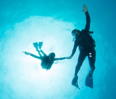 Two divers underwater holding hands