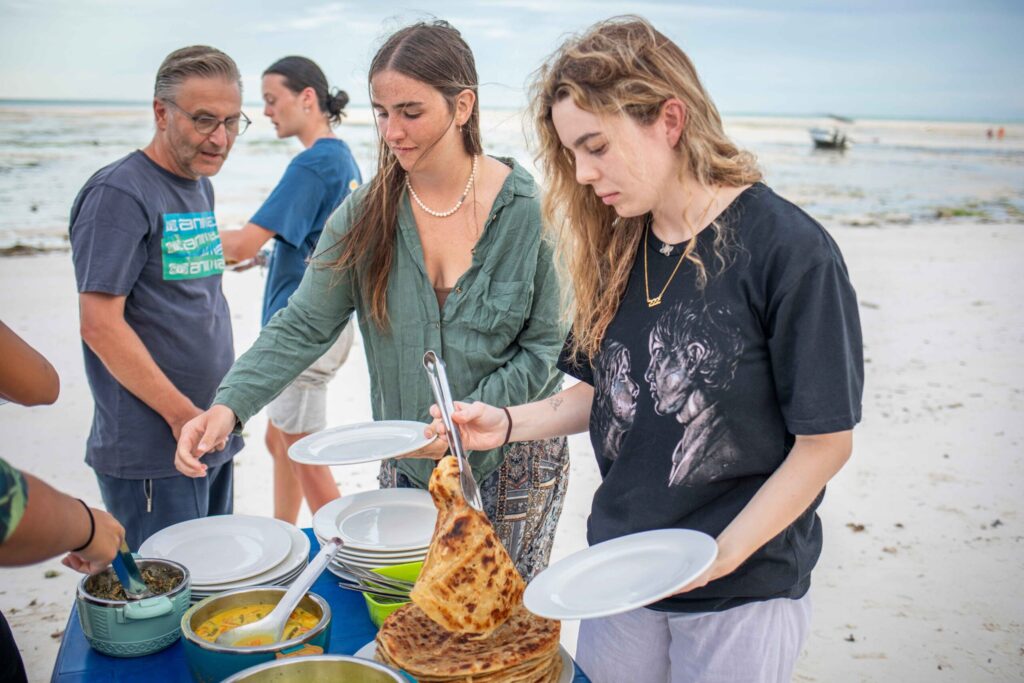 travellers having a cooked meal on the beach, Zanzibar