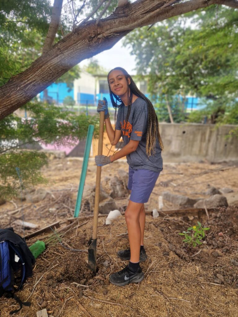 girl traveller in Ecuador with long braided hair holding a shovel