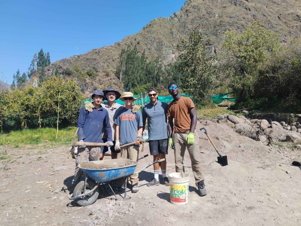Group of traveller students on a project work site posing for a photo in Peru