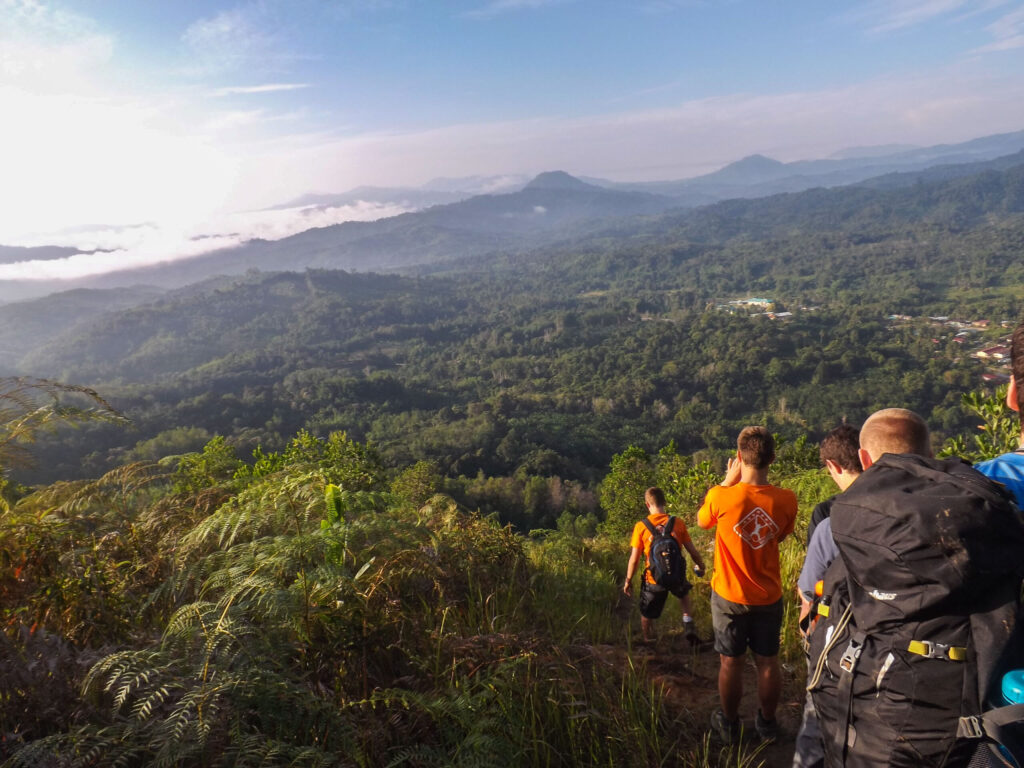 Stuednt travellers walking in the jungle in Borneo with beautiful view of the mountains ahead of them