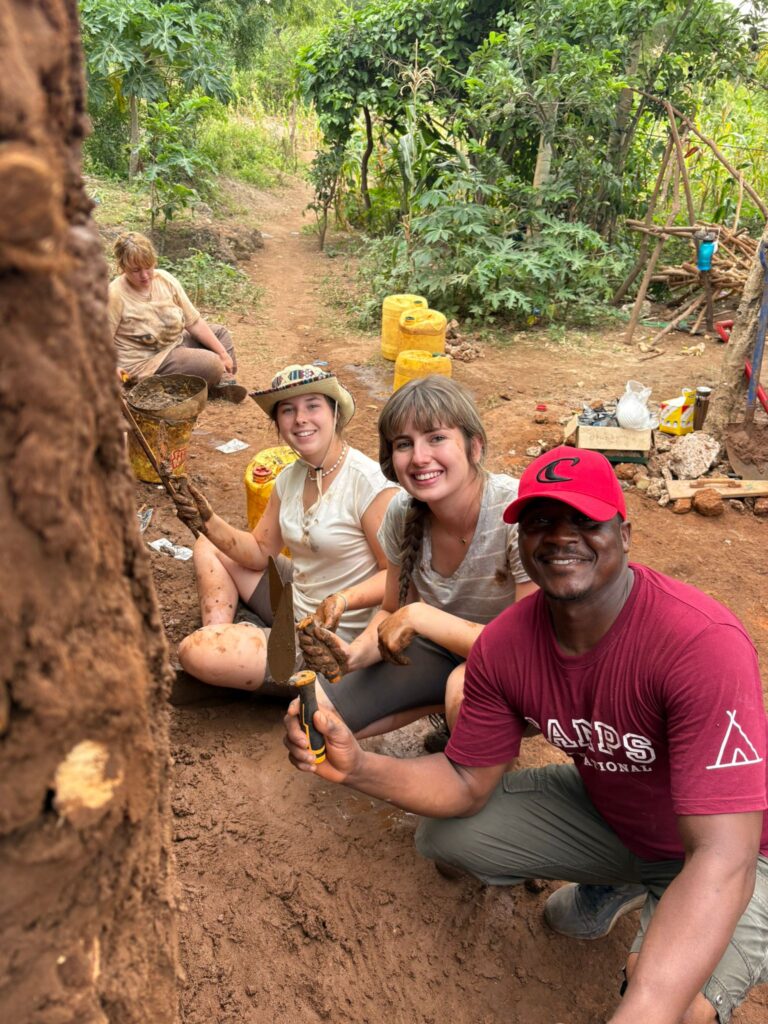 Student travellers and a local from Kenya posing tohether as they work on building a mamas house