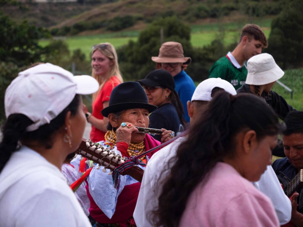 Student travellers standing with local people in Ecuador playing traditional instruments