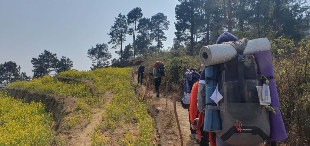 group of travellers with backpacks hiking in nepal on a green path with trees
