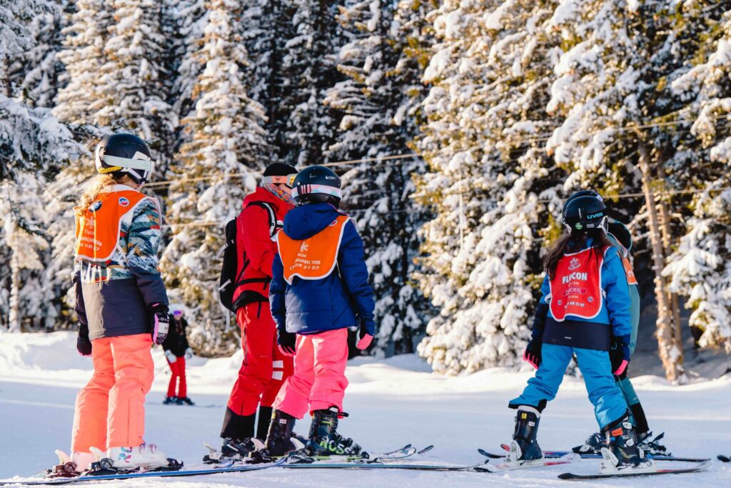 Skiers that are standing up talking to each other while wearing snowboards.