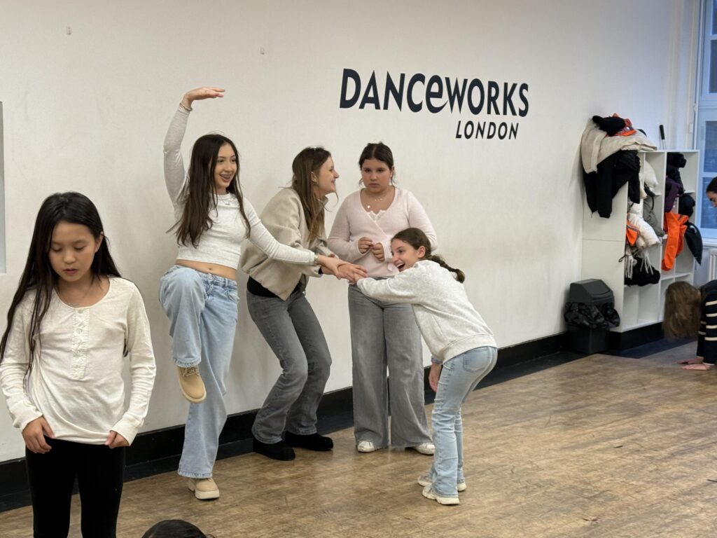Group of female students in a dance studio practicing for a dance recital.