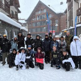 A group of people in a snow-covered village with snow falling down.